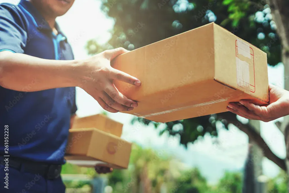 Nhân viên giao hàng trao kiện hàng cho khách hàng
